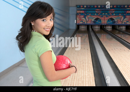 Young woman at bowling alley holding ball, portrait Stock Photo