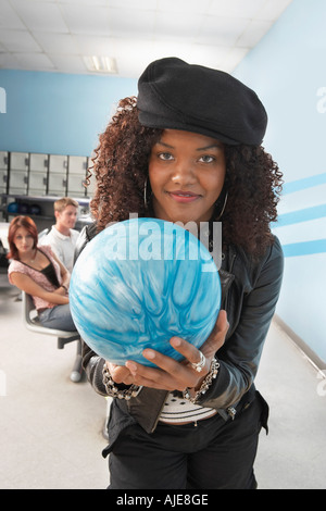 Young woman at bowling alley holding ball, portrait Stock Photo