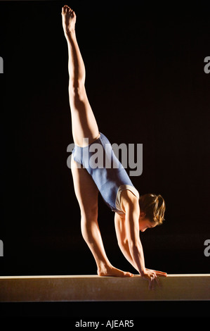 Gymnast (13-15) striking pose on balance beam Stock Photo