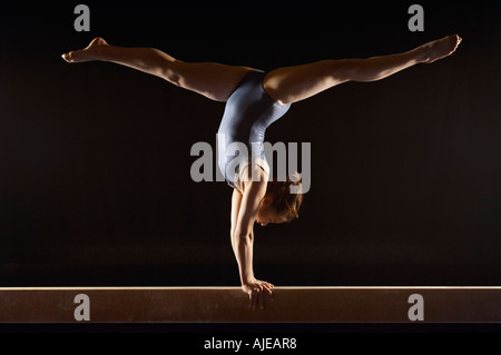 Gymnast (13-15) doing split handstand on balance beam, side view Stock Photo