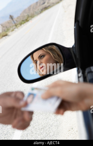 Woman sitting in car handing diving licence to police officer Stock Photo
