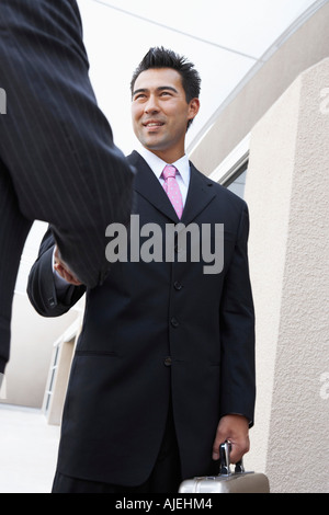 Two Businessmen Shaking Hands outside office, low angle view Stock Photo