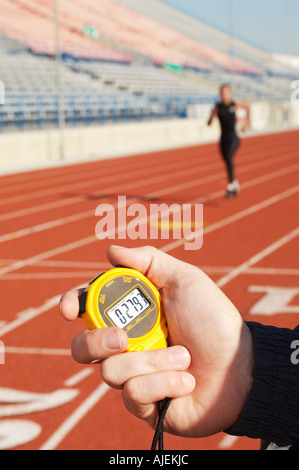 Man holding stopwatch, close up of hand, timing runner on running track Stock Photo