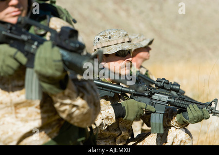 Soldiers aiming rifles in field Stock Photo