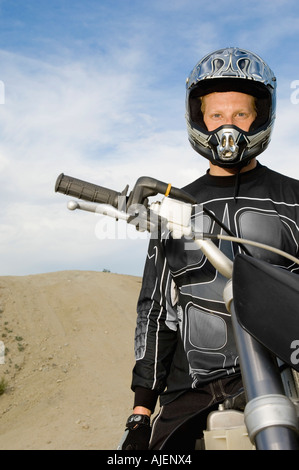 Motocross racer on bike in desert, (portrait) Stock Photo