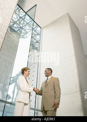 Businesspeople shaking hands in office building, (low angle view) Stock Photo