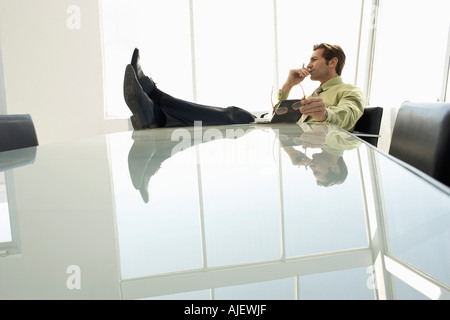 Businessman with feet up in conference room Stock Photo