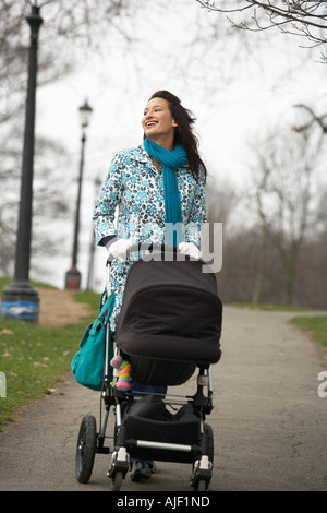 Mother walking with baby carriage in park Stock Photo