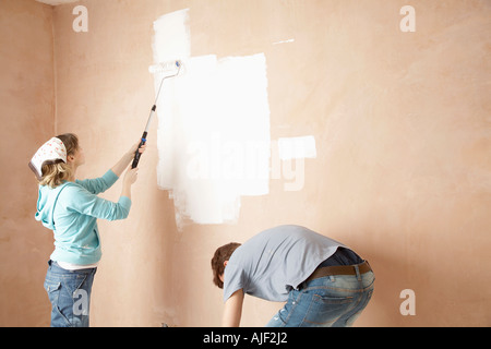 Couple using paint rollers on interior room Stock Photo