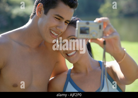 Couple photographing themselves, standing in park Stock Photo