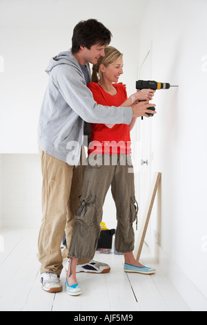 Young woman holding drill at new home celebrating crazy and amazed for ...