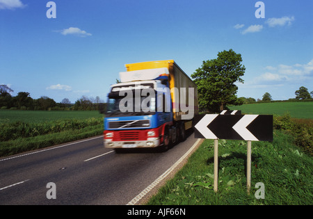 lorry passing black and white chevron warning sign of sharp bend in road uk Stock Photo