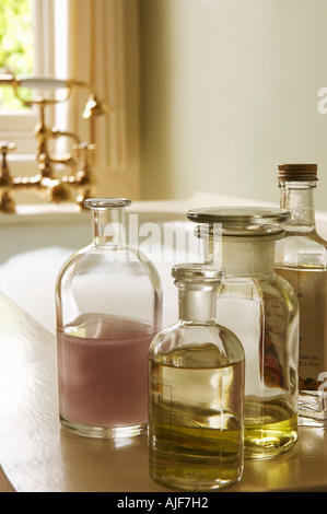 Bottles of Bath Oils on edge of bathtub filled with bubbles Stock Photo