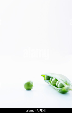 Open pea pod containing peas and single pea, close-up Stock Photo