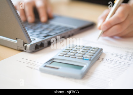 Woman using laptop and calculator, close up Stock Photo