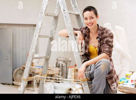 Female interior decorator sitting on ladder in work site, portrait Stock Photo