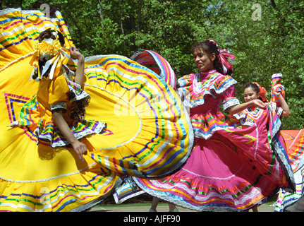 Young Hispanic girls perform Mexican folkloric dance wearing dresses ...