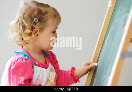 Two year old girl drawing on chalk board Stock Photo