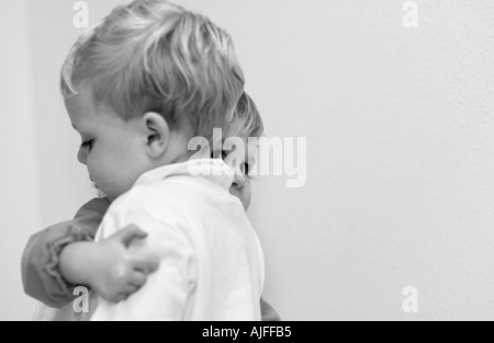 Two year old boy and girl hugging with girl peeking out from behind Stock Photo