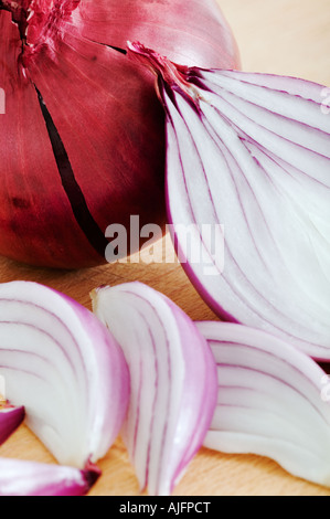 Red onions on wooden cutting board Studio shot against white background Stock Photo