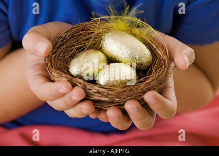 Child holding a basket with golden Easter eggs Hands only Studio shot Model Released Stock Photo