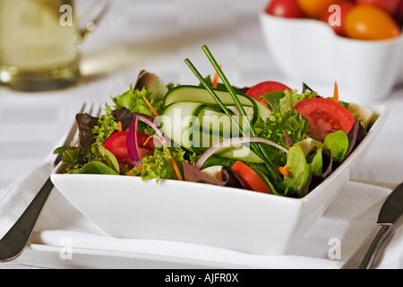 Fresh mixed salad with tomato red onion salad leaves cucumber and cheese in white porcelain bowl Stock Photo