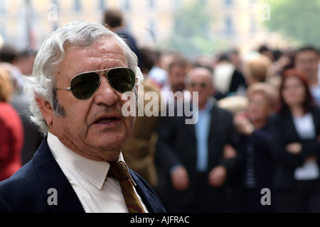 A man wearing sunglasses in front of a crowd in Seville Spain during Holy Week Stock Photo