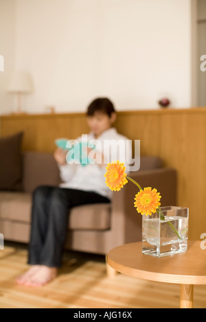 Young woman reading book sitting on sofa Stock Photo