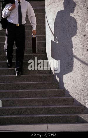 Caucasian businessman walking down stairs with shadow Stock Photo