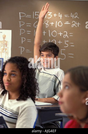 Latino male student raising hand in middle school math class Stock Photo