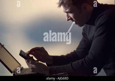 Man using PDA working on laptop computer in home office Stock Photo