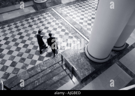 Two businessmen walking and talking in lobby Stock Photo