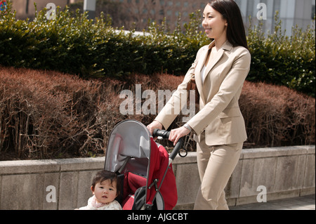 Businesswoman pushing baby stroller Stock Photo