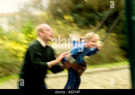 Caucasian man pushing daughter on swing Stock Photo