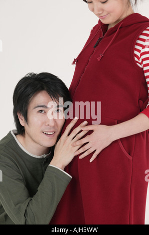 Husband holding ear to his wife's stomach Stock Photo