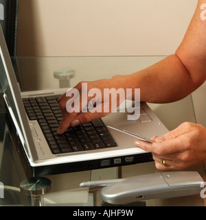 Womans Hands Hold Credit Card Using Laptop Computer Online ordering buying goods over the net Stock Photo