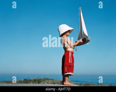 Boy holding toy boat Stock Photo