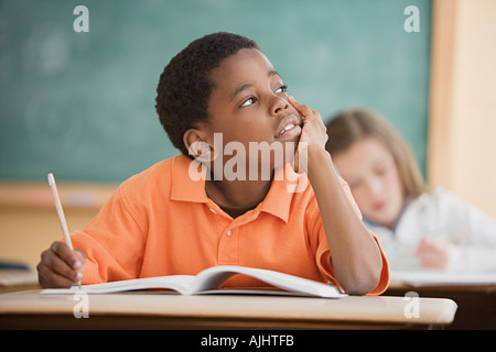 Schoolboy daydreaming in classroom Stock Photo