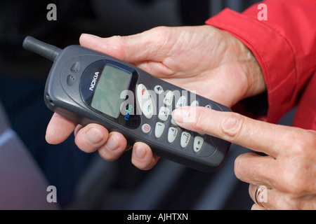 Close up of womans finger dialing on old Nokia mobile phone UK Stock Photo