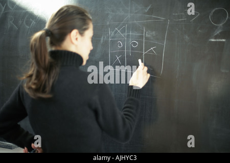 Young woman drawing noughts and crosses on a blackboard Stock Photo