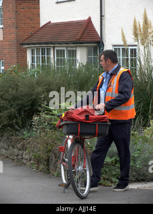 Postman delivering mail on bicycle in village of Didcot England UK Stock Photo