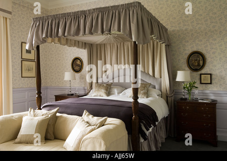 Fourposter bed and sofa in bedroom with patterned purple wall paper in 17th century Irish castle Stock Photo