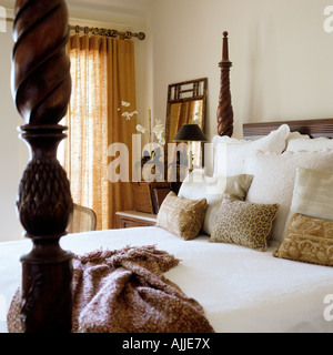 Fourposter bed with carved bed poster, cushions and throw Stock Photo