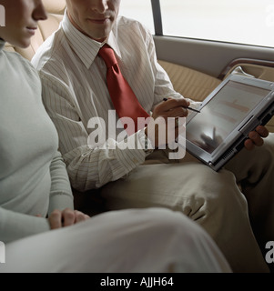 Business people using laptop in taxi Stock Photo