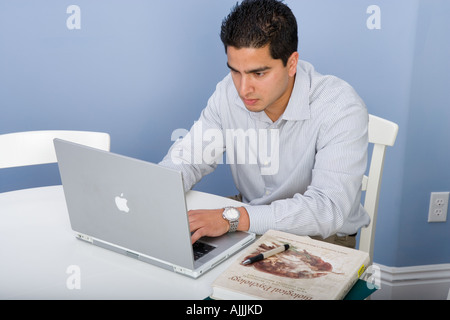 young Indian male college student studies while using Macintosh  laptop computer Stock Photo
