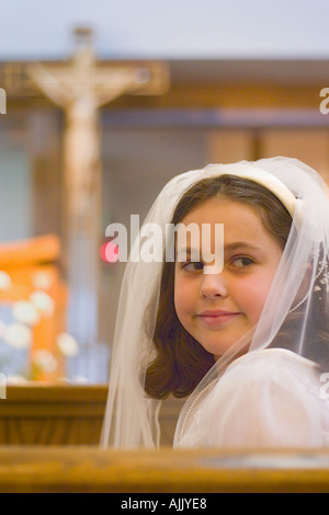 Young girl smiling in church during first communion mass Stock Photo