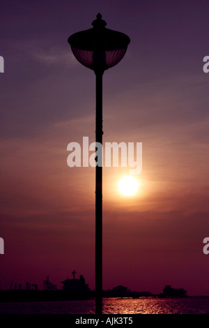 A close-up shot of a lamp post with the setting sun as backdrop Stock Photo
