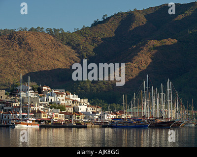OLD TOWN MARMARIS WITH MASTS OF MOORED SAILING BOATS AND GULETS  FLANKED BY SURROUNDING HILLS TURKEY Stock Photo