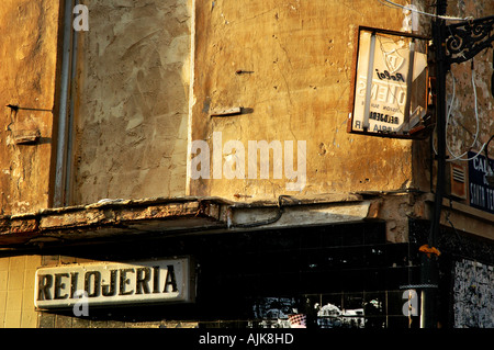 derelict watch and clock shop with broken electric sign lit by early evening light in the city of Valencia Spain Stock Photo