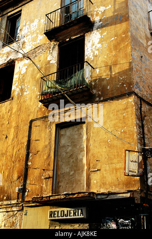 derelict watch and clock shop with distressed walls lit by early evening light in the city of Valencia Spain Stock Photo
